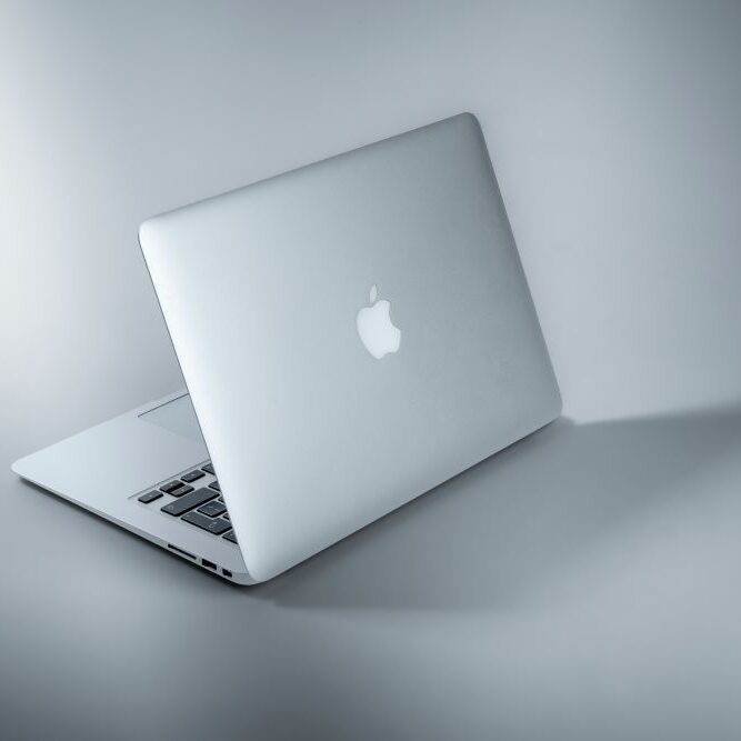 An apple computer on display on a plain gray background.