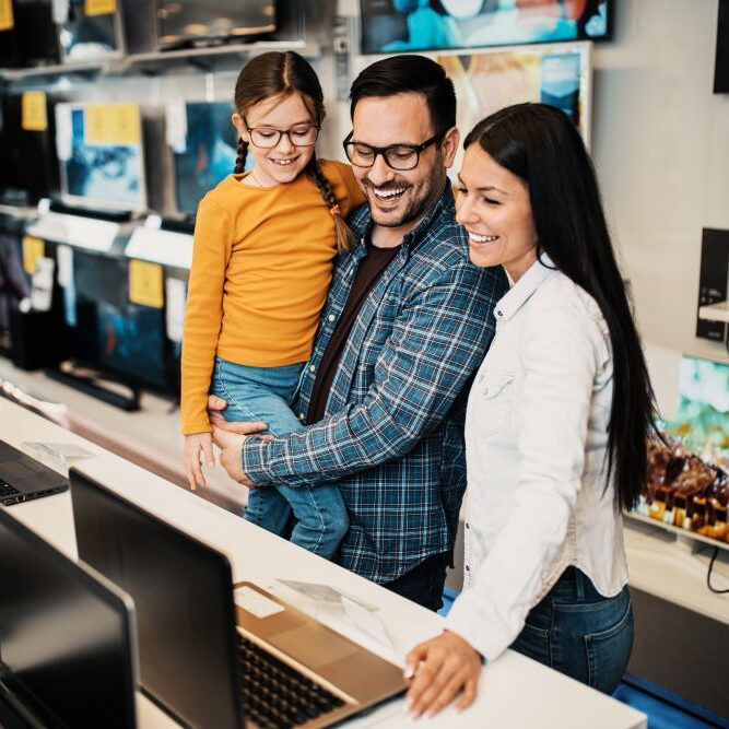 Happy family buying laptop in a computer store.