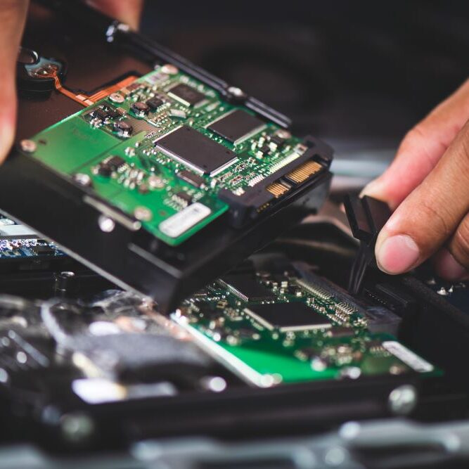 A computer repairman replacing computer parts in a broken computer.