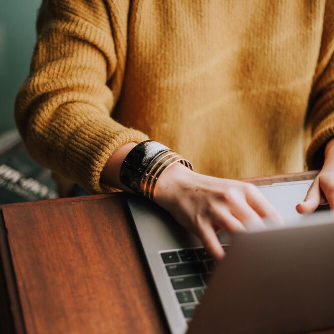 A woman working on her computer to complete a project at work.